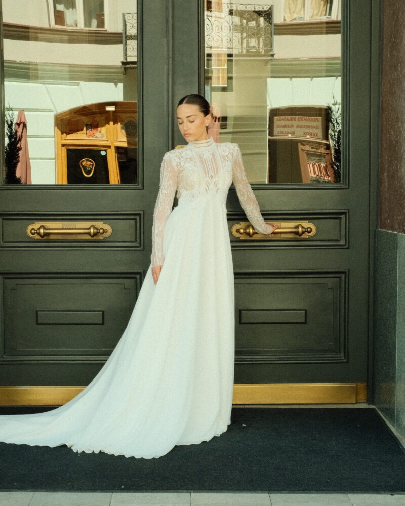 Vintage-inspired lace wedding dress with a high neckline, long sleeves, and sheer back, Chic Delight Photo 02